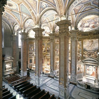Santa Maria dell'Anima, view towards the left nave Church interior showcasing intricate frescoes, towering columns, and wooden pews.