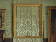 Empty ornate frame on patterned wall, flanked by two artworks.