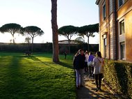 People walking along a path beside a building in a park setting.