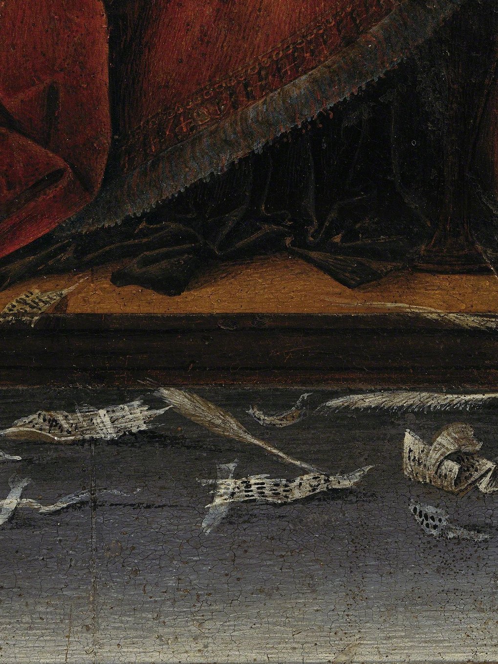 Ornate red fabric draped over black cloth, scattered torn paper on a wooden surface.