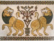 Two mosaic lions facing a decorative tree.