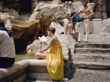 Lesende Frau auf einer steinernen Treppe.
