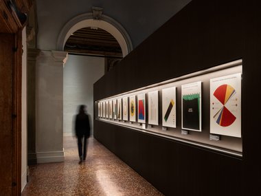 Kunstgalerie mit beleuchteten Grafiken und einer Person im Gang.