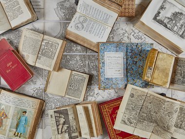 Verschiedene Bücher liegen aufgeklappt auf einem Tisch.